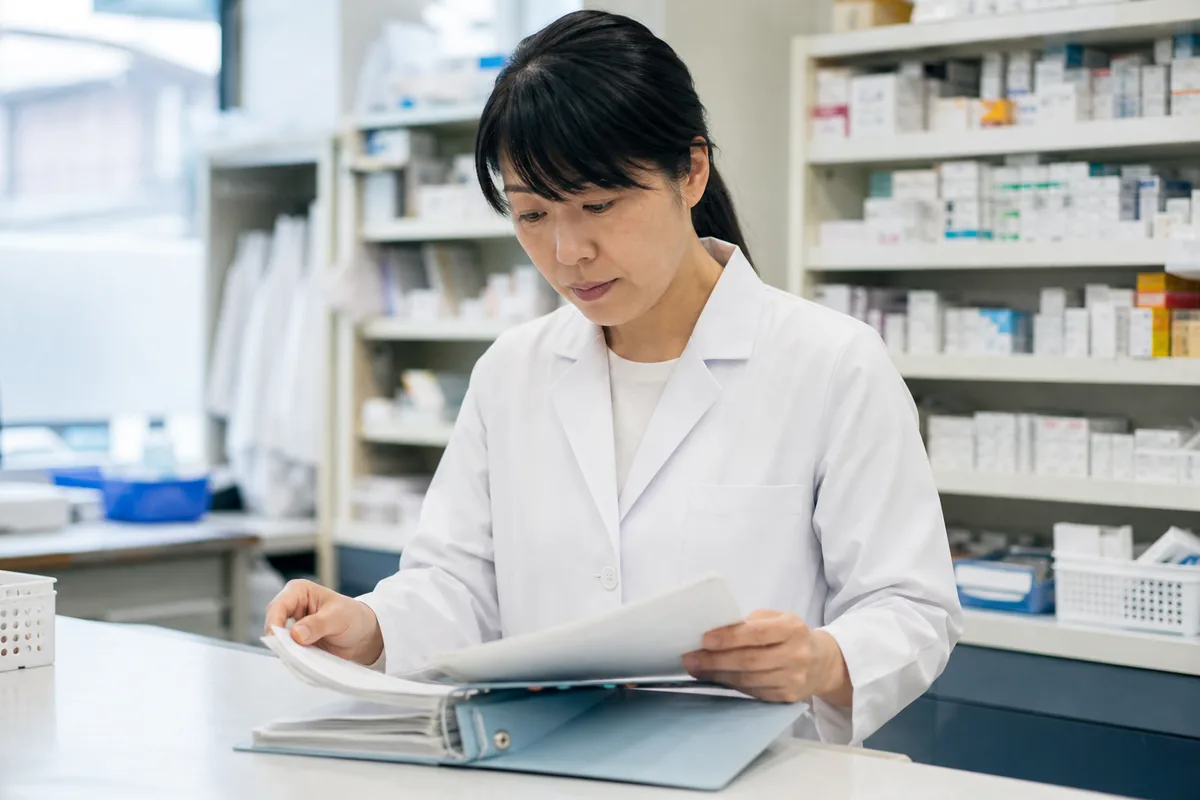 薬局のバックヤードで訪問記録を確認する薬剤師